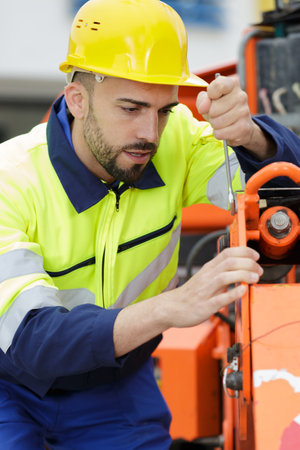 young male engineer standing beside a tractorの写真素材