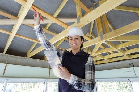 female contractor pointing to wooden beamsの写真素材