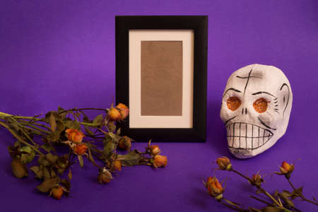 Day of the dead, mexican tradition concept with photo frame for remembrance, sugar skull and dry flowers on violet backgroundの写真素材