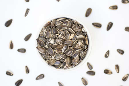 Sunflower seeds on a bowl with white background. Healthy vegetarian foodの写真素材