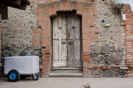 VAL'QUIRICO, TLAXCALA, MEXICO- MARCH 25, 2017: Facade with a stone wall with bricks and an ancient door in Val'Quirico, Tlaxcala, Mexicoのeditorial素材