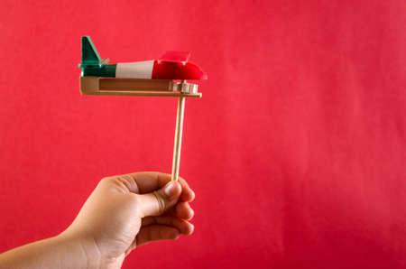 Hand holding a noisemaker against red backgroundの写真素材