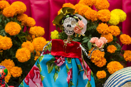 OAXACA, OAXACA, MEXICO- NOVEMBER 1, 2017: Little skull dressed with traditional clothes and yellow flowers, part of a mexican Day of the Dead offering altarのeditorial素材
