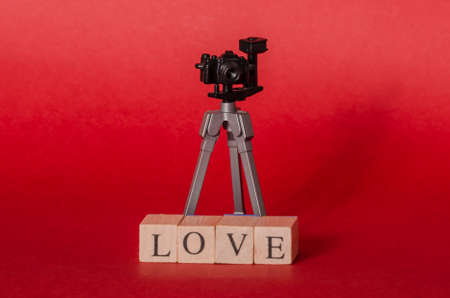 Toy camera and wooden cubes with the word love against red backgroundの写真素材