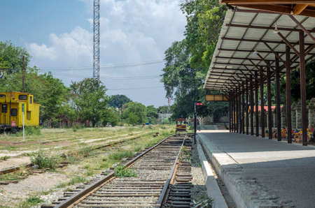 OAXACA, OAXACA, MEXICO- JUNE 1, 2018: Landscape with tracks and a yellow carriage in a sunny day at Ferrocarril Museum in Oaxaca, Mexicoのeditorial素材
