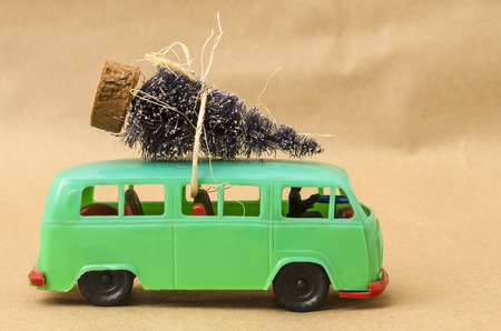 Green toy van with Christmas tree against brown background. Retro car with Christmas treeの写真素材