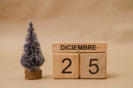 Christmas tree beside wooden block calendar set on the Christmas date 25 december on brown...