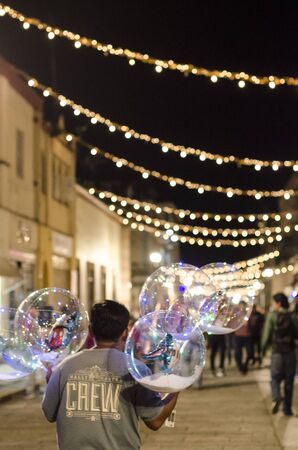 OAXACA, OAXACA, MEXICO- JANUARY 2, 2019: Kid selling lighting ballons in the street at night in Oaxaca, Mexicoのeditorial素材