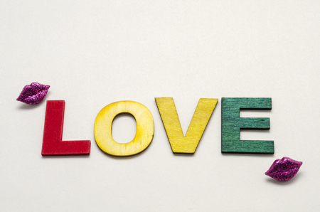 Love word made with colorful wooden letters and decorated with little lips shape buttons against white backgroundの写真素材