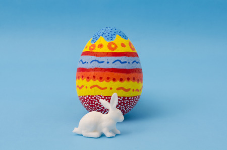Colorful egg decorated and white bunny on blue background. Decoration for Easter Dayの写真素材