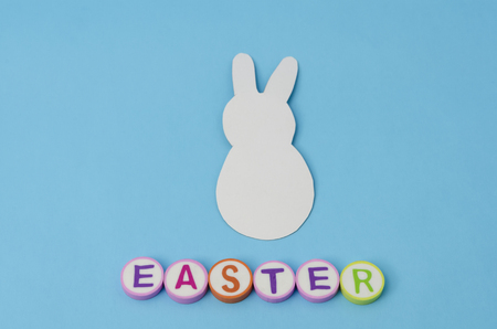 White paper bunny and easter made form colorful letters on blue background. Decoration for Easter Dayの写真素材