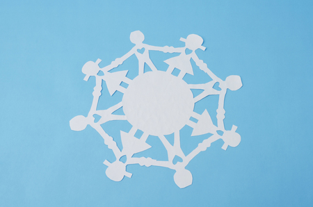 Paper doll chain against blue background. Paper doll chain made from white paper on blue backgroundの写真素材