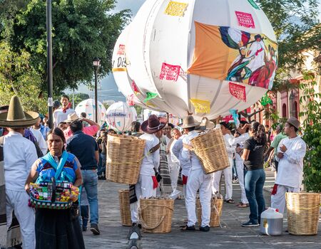 OAXACA, OAXACA, MEXICO- JULY 6, 2019: Young men dressed with traditional clothes and carrying big balls called marmotas during the Convite, a party made for invite to a big traditional party called Guelaguetza in Oaxaca, Mexicoのeditorial素材