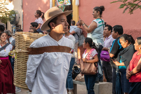OAXACA, OAXACA, MEXICO- JULY 6, 2019: Young man carrying a basket during the Convite, a party made for invite to a big traditional party called Guelaguetza in Oaxaca, Mexicoのeditorial素材