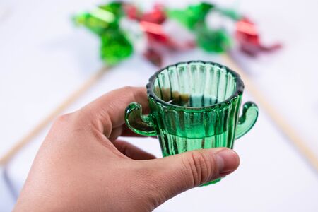 Woman hand holding a glass of tequila with two pinwheels as background. Mexican Independence Day celebrationの写真素材