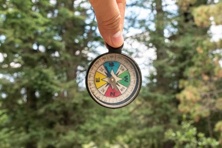 Woman's fingers holding a colorful compass at the forest. Trip at the forestの写真素材