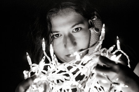 Black and white photography of a young latin woman with a rubber chicken, looking at Christmas...