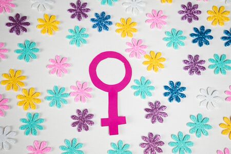 The female gender symbol made from pink paper and colorful little flowers on white backgroundの写真素材