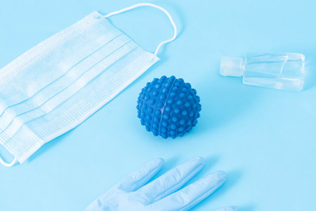 Flat lay photography with face mask, globes, sanitizer gel and abstract virus strain on blue...
