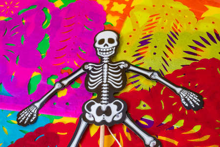 Articulated smiling skeleton resting on colorful cut paperの写真素材