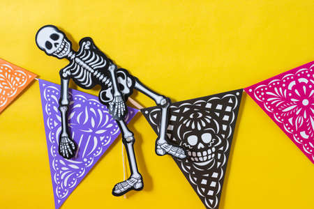Articulated skeleton on a colorful day of the dead banner on yellow backgroundの写真素材