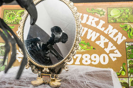 XALAPA, VERACRUZ, MEXICO- OCTOBER 8, 2020: Raven skeleton looking at the mirror and Ouija board at bottom. Halloween decorationのeditorial素材