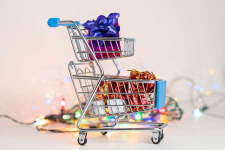 Supermarket cart with christmas presents and christmas lights at bottom, on white backgroundの写真素材