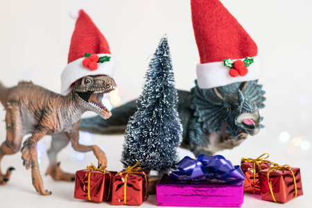 Toy dinosaurs with Santa Claus hats, a christmas tree and presents on white background. Christmas...