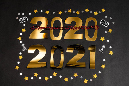 2020 and 2021 made with golden numbers, stars and confetti on black background. New Year decoration