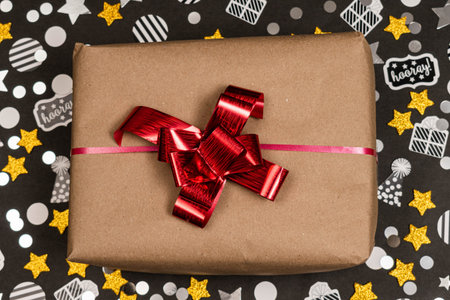 Present with red ribbon, golden stars and confetti on black background. Party, Christmas and New Year decorationの写真素材