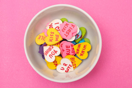White bowl with colorful little hearts with love phrases on pink background. Valentine's Dayの写真素材
