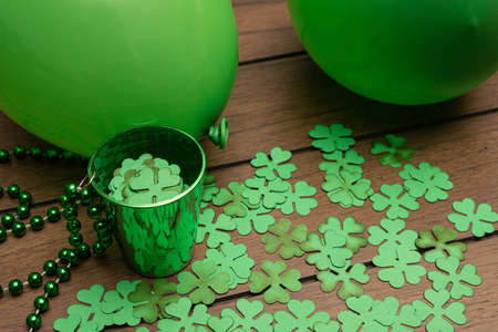 Green cup with shamrocks and two green balloons on wooden background. Saint Patrick's Day celebrationの写真素材