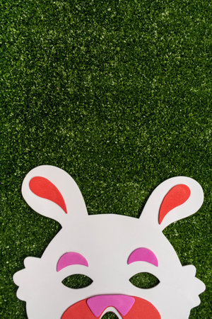 Easter bunny mask on green grass background with copy space. Easter decoration