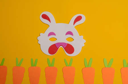 Cute bunny mask and "Happy Easter", phrase made from wooden letters on yellow backgroundの写真素材