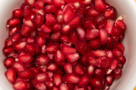 Close up of fresh seeds of pomegranate on white bowl