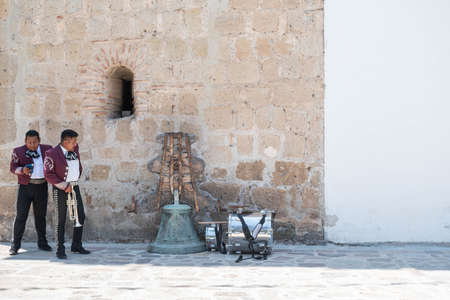 TLACOLULA, OAXACA, MEXICO- MAY 23, 2022: Members of mariachi waiting outside of Parroquia Santa Maria de la Asuncion, in a sunny day at Tlacolula, Oaxaca, Mexicoのeditorial素材