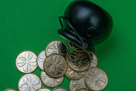 Black pot and golden coins with clovers on green background. Decoration for St. Patrick's Day celebrationの写真素材