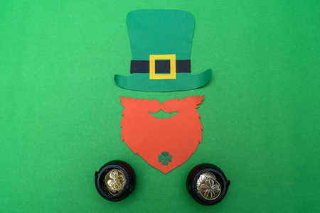 Saint Patrick's Day leprechaun and two black pots full of golden coins with clovers on green backgroundの写真素材