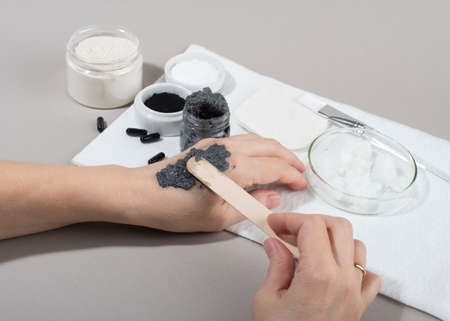 Womans hands testing charcoal facial mask on hand skin. Close up. Home beauty concept.の写真素材