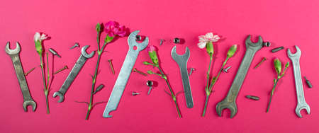 Labor Day background concept, 1 May concept. Wrench and clove pink carnation flower on pink background. Flat lay, top view. Banner.の写真素材