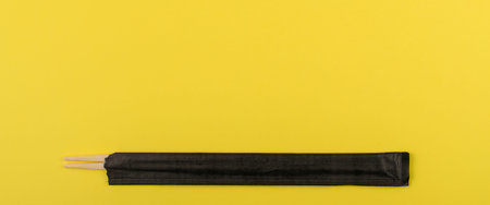 Wooden chopsticks on yellow background. Wide banner. Flat lay, top view. Copy space.