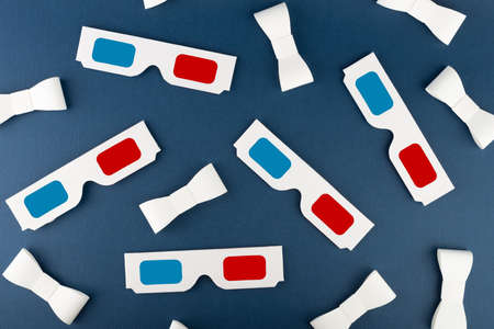 Flat lay composition with classic 3D movie glasses and paper ribbons on dark blue background. Conceptual studio shot.の写真素材