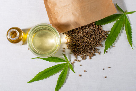 Cannabis seeds, young hemp leaves and cosmetics CBD oil on white background. For cosmetic, treatment, therapy. Flat lay, top view.の写真素材