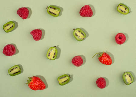 Fruit of actinidia arguta, kiwi berry fruits and raspberries on green background.の写真素材