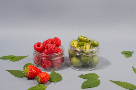 Fruit of actinidia arguta, kiwi berry fruits, raspberries, strawberries and mint leaves, on blue...
