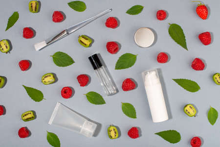 Fruit of actinidia arguta, kiwi berry fruits, raspberries, mint leaves and cosmetic containers on blue background.の写真素材
