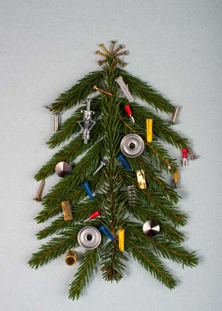 Christmas tree decorated with nails and screws on grey background.の写真素材
