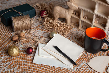 Preparation for Christmas holidays. Table with decorations, cup of coffee, pen and blank cards for greeting.の写真素材