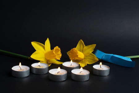 Pray for Ukraine. Burning candles, yellow flowers and blue ribbon. Stop war 2022.の写真素材