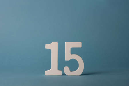 White wooden number fifteen 15 on blue background.の写真素材